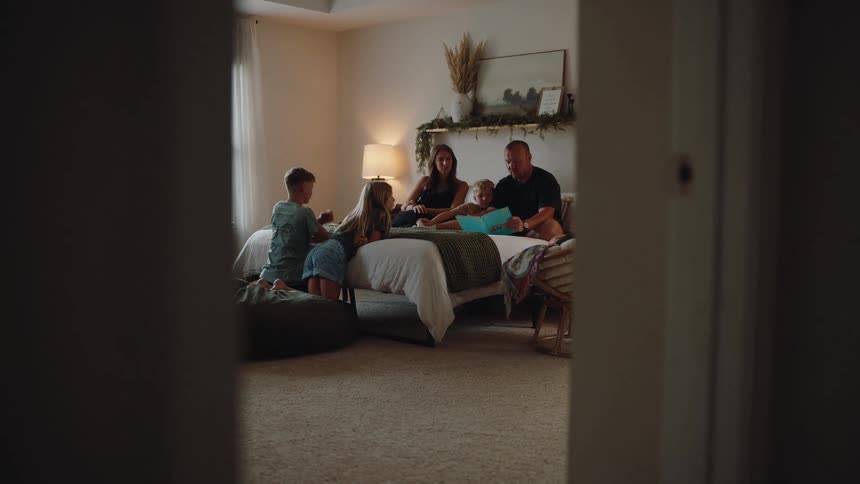 Father and mother sitting in the room reading a story to their children