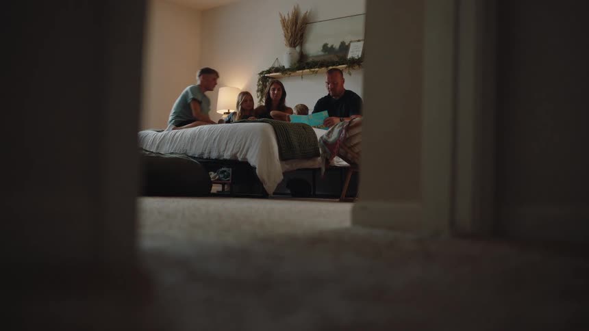 A father is reading to his family in bed