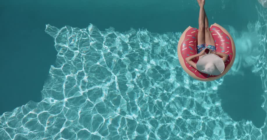 Person wearing a hat relaxes on a donutshaped pool float