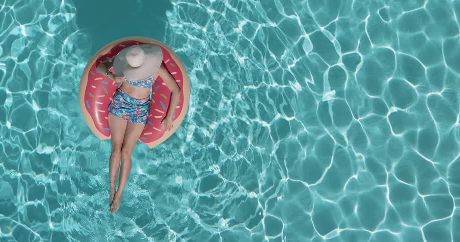 The woman floats on a tube shaped like a donut in the pool