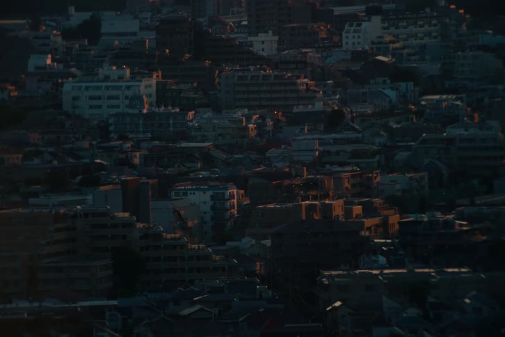 A view of a dense city at sunrise shows the warm light of the sun hitting the tops of the buildings and creating a peaceful and quiet morning atmosphere