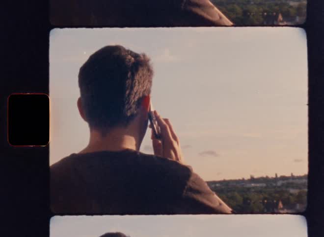 A person talks on a cell phone looking out over a city landscape