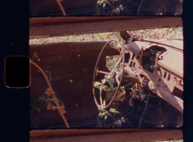 Cinematic close-up of a rusted, abandoned car interior overgrown with vines and foliage, featuring a decaying steering wheel and dashboard, captured with nostalgic texture, film grain, and vintage imperfections on Super 8mm film