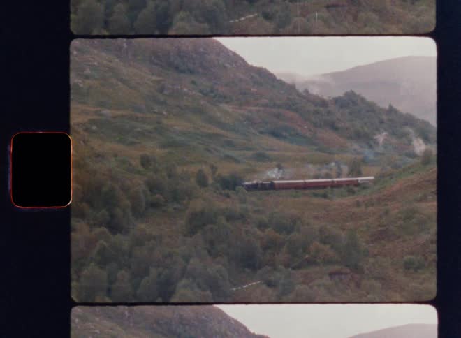 A train rolls by some hills