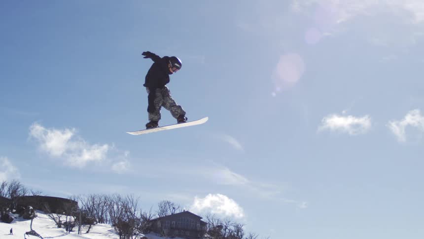 The person is jumping high on his snowboard