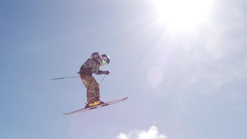 Skier jumps in the air against a sunny blue sky