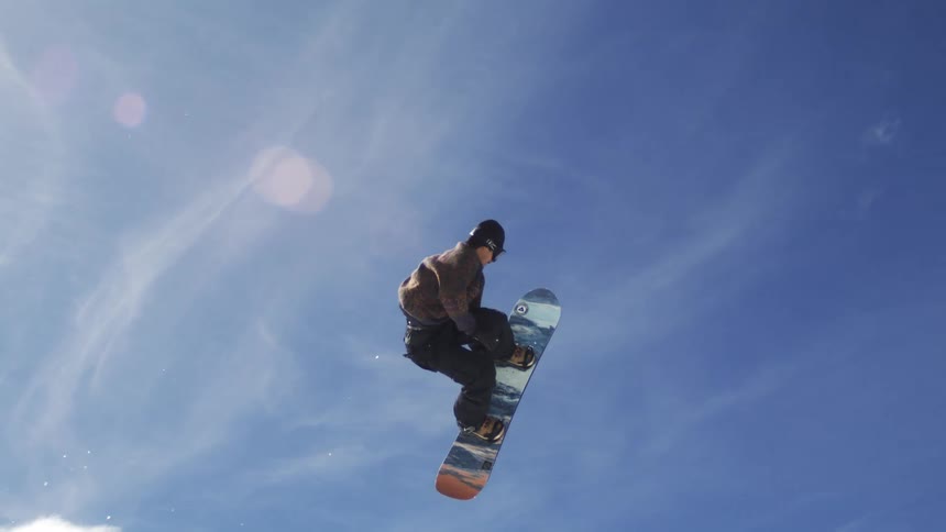 The man takes a large leap on the snowboard