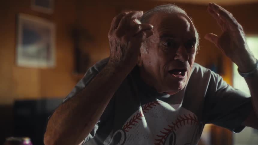 The man cheers while holding a baseball