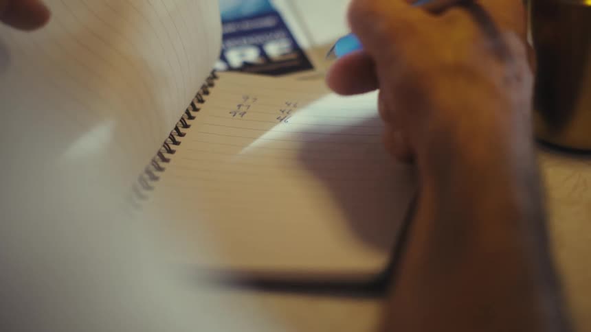 Elderly man writes in a notebook with a pen