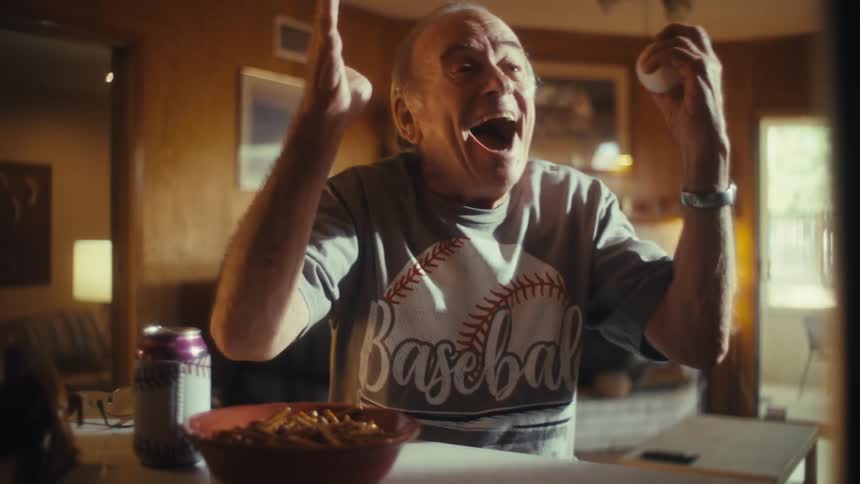 The man cheers and smiles while watching baseball