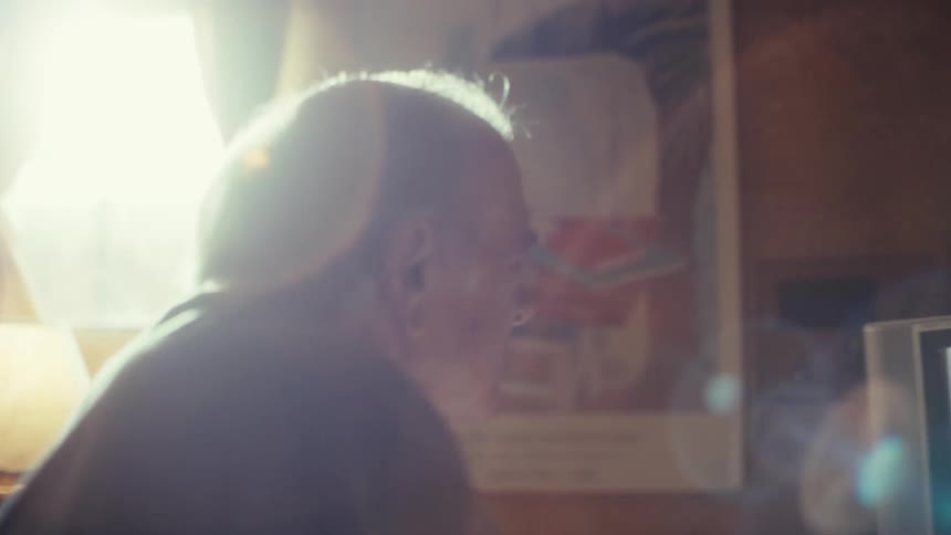 The man is talking and waving his hand at the television