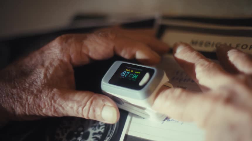 The man gets a reading from a finger heart monitor