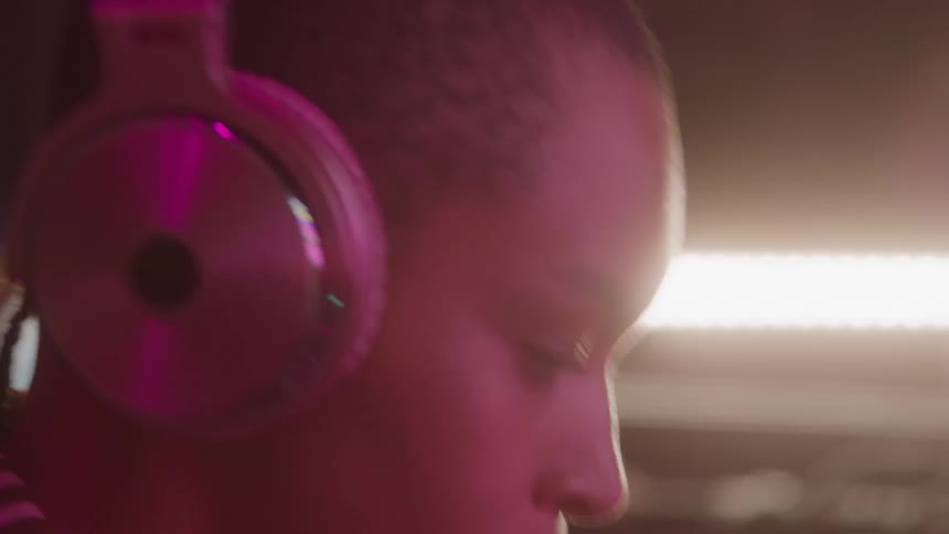 Woman wearing headphones looks attentively in a lit studio