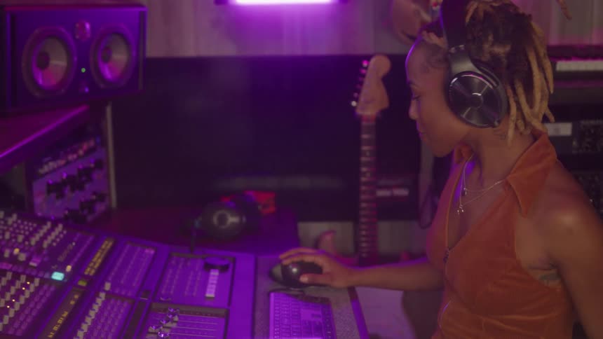 Woman with headphones enjoying music in front of a mixer in a studio