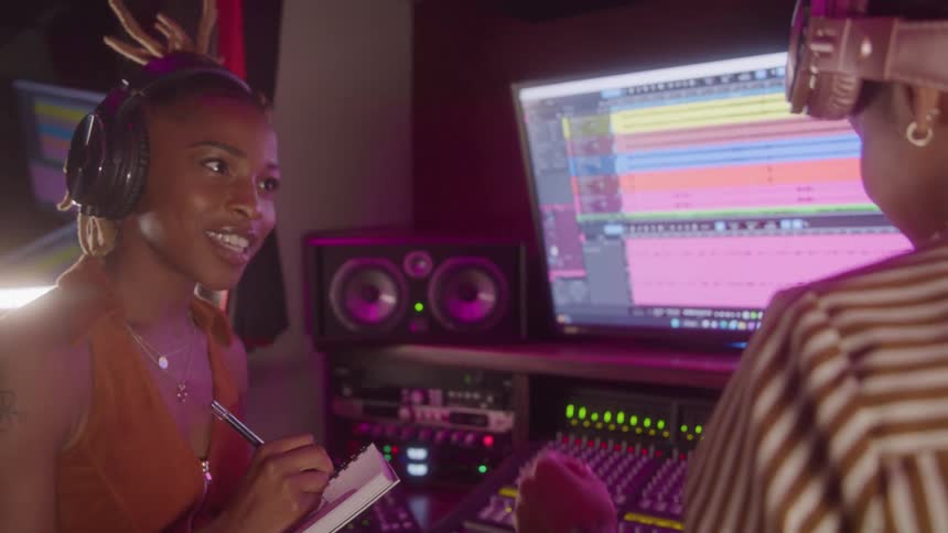Woman taking notes and the other is singing in a studio