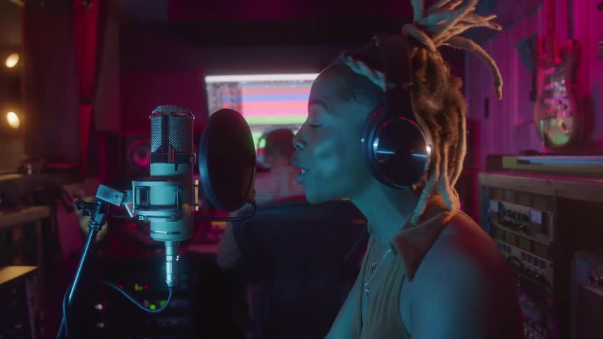 Singer wearing headphones recording in a studio in front of a microphone