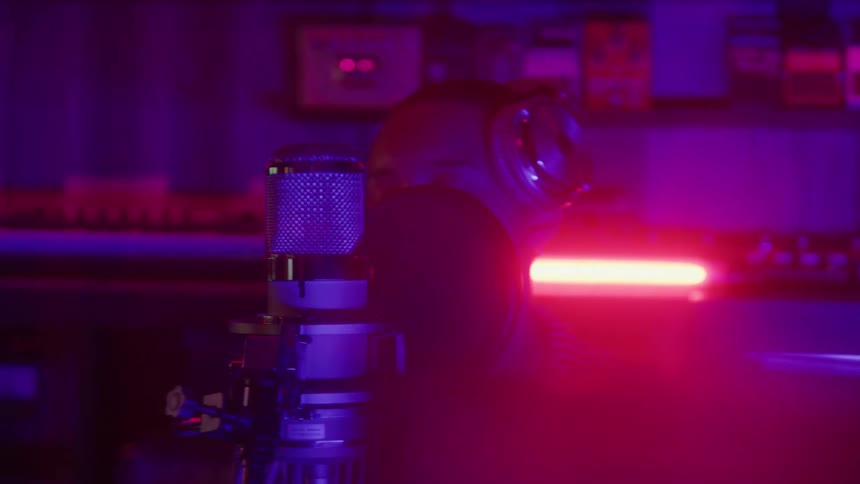 Person with headphones singing into a microphone in a studio