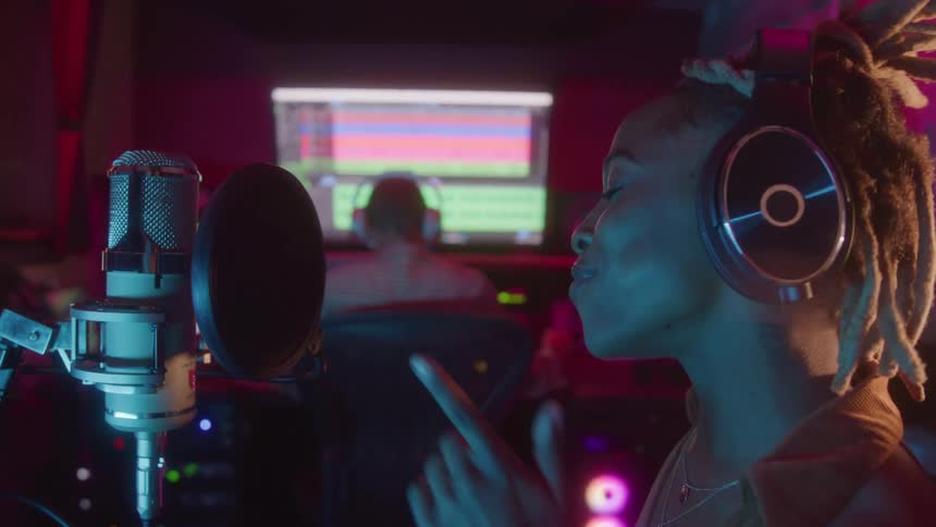 A musician sings into a microphone while recording in a studio