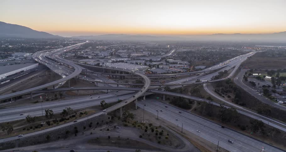 Aerial of busy freeways and overpasses in a metropolitan city at sunset