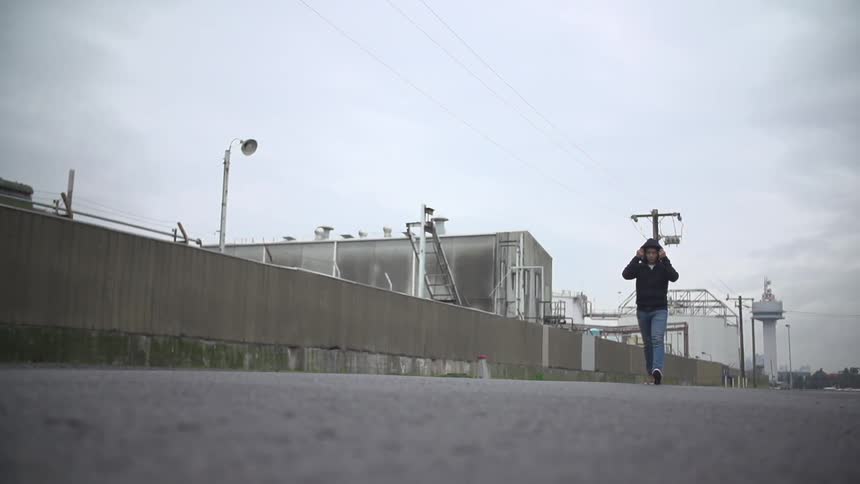 A man walks the gravel pathway beside a utility plant