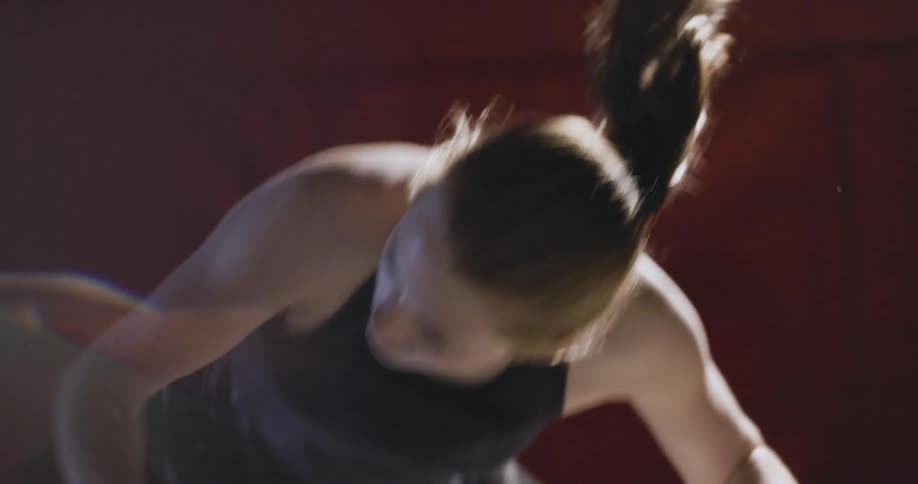 A woman in athletic wear stretches forward with focus balancing her weight on one arm in a fitness setting