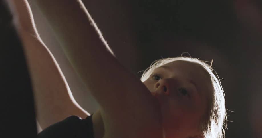The video shows a closeup of a young womans face and arms as she exercises her facial expression appears strained suggesting the physical effort involved in her workout the lighting is low with a key light from the left side casting a soft glow on