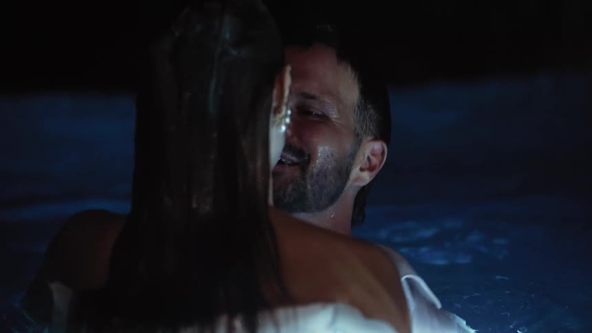A man and woman hug and kiss in the pool