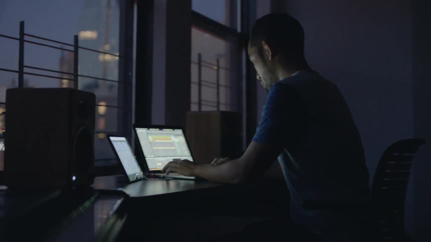 Man nods his head as he types on his laptop at night
