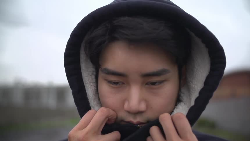 A man adjusts the hood of his jacket