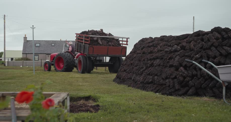 Elderly man waving hand while sitting on a tractor at farm