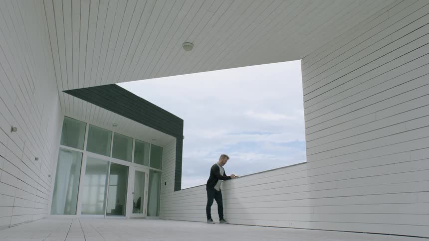 A man leans against a ledge from atop a building