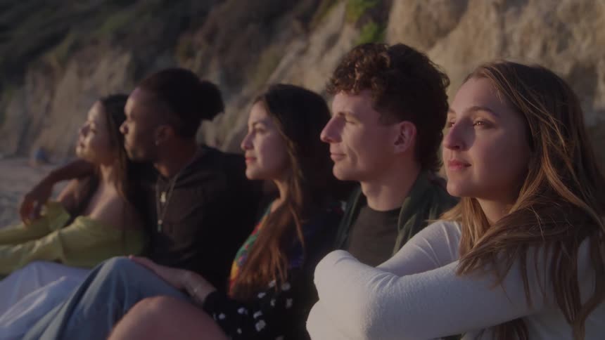 Friends sit together on the sand