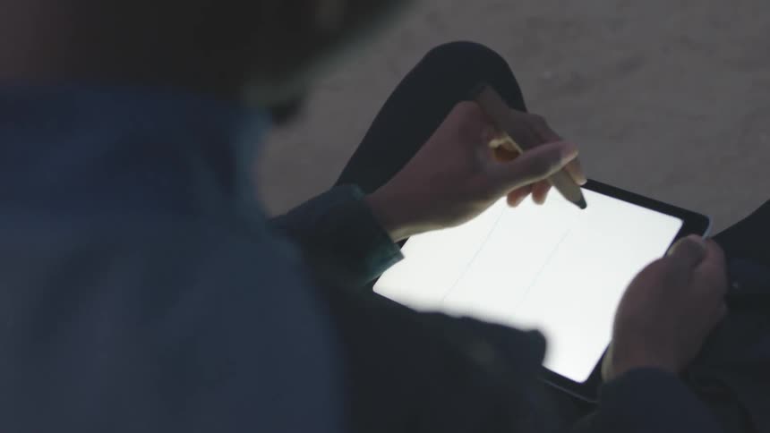 A man writes on a tablet screen