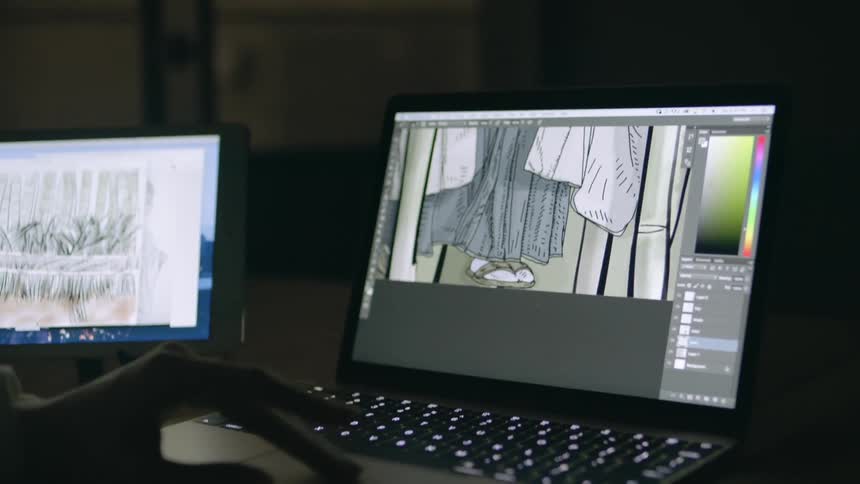 A person is using laptops to work on a graphic design
