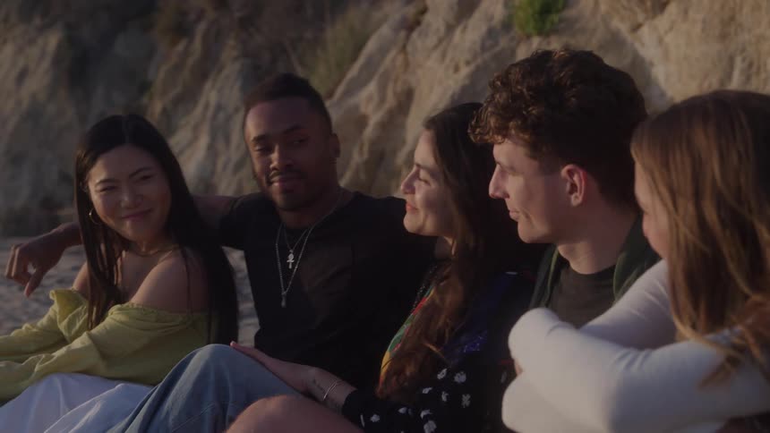 Friends sitting side by side in front of a hillside during sunset