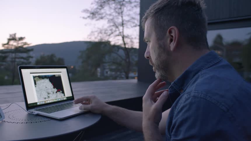 A man is using a laptop looking over a view