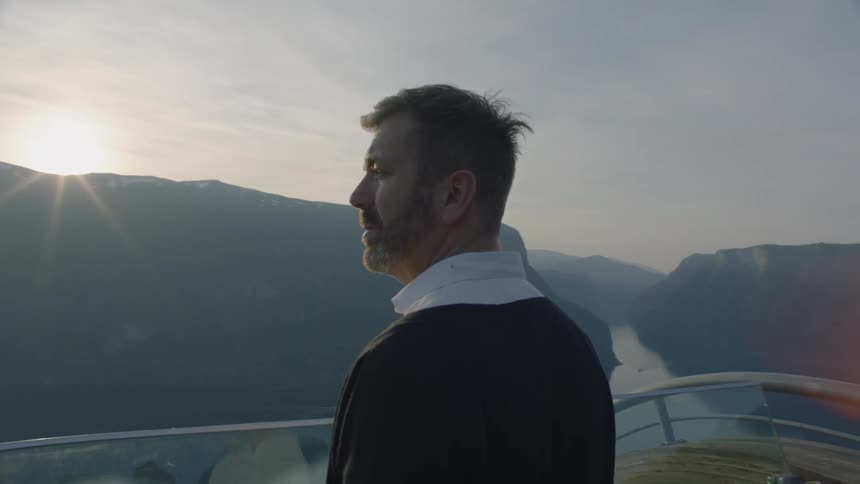 A man looks out over a view of a mountain range