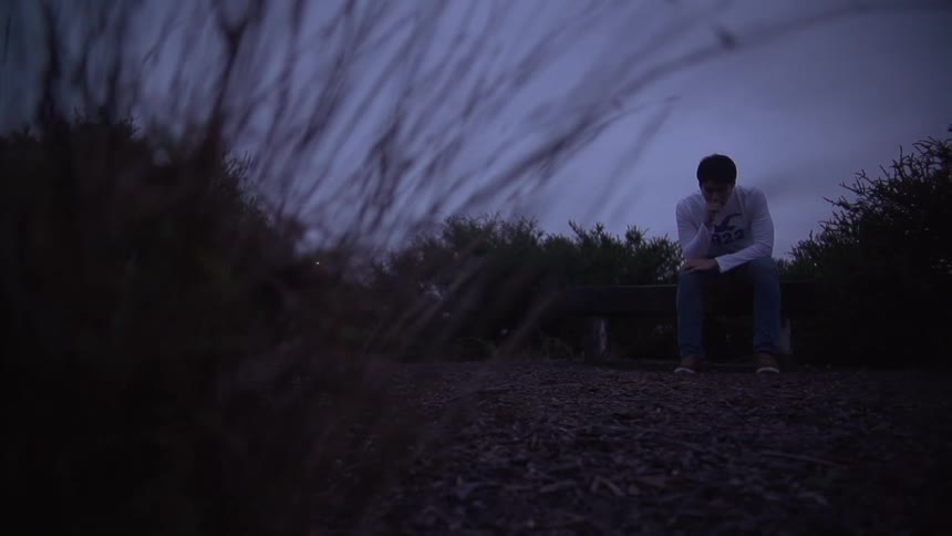 Person sitting thoughtfully on a bench beside a path