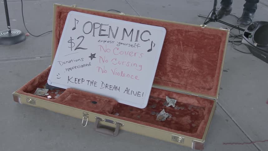 A man plays music on the sidewalk