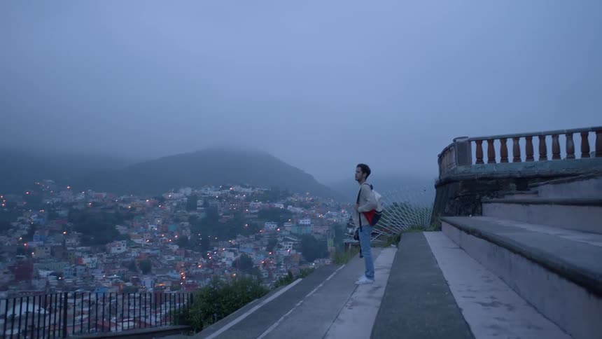 A man looks out over a view from top of a hill