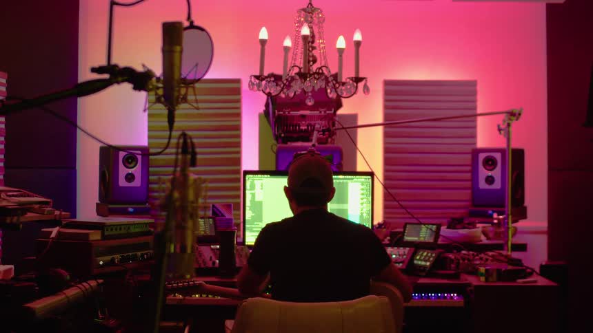 A music producer works on a computer in a colorful studio