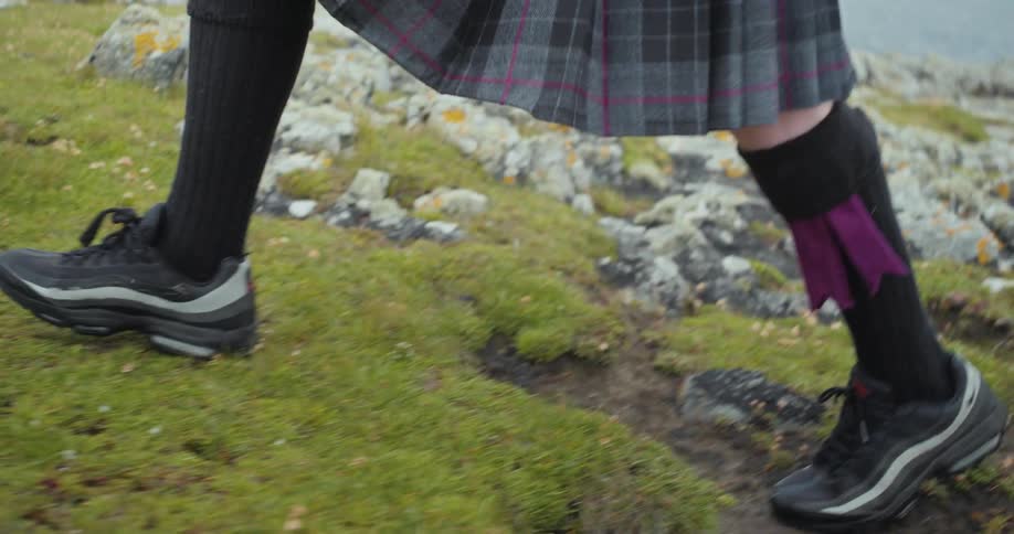 A woman walks along a rocky coastal landscape by the ocean