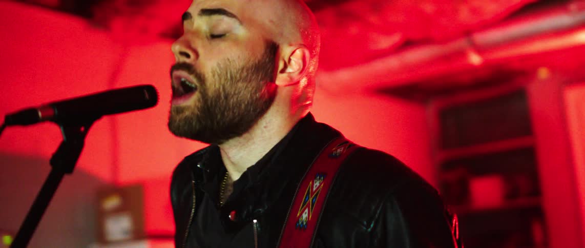 Bald and bearded man singing in a performance