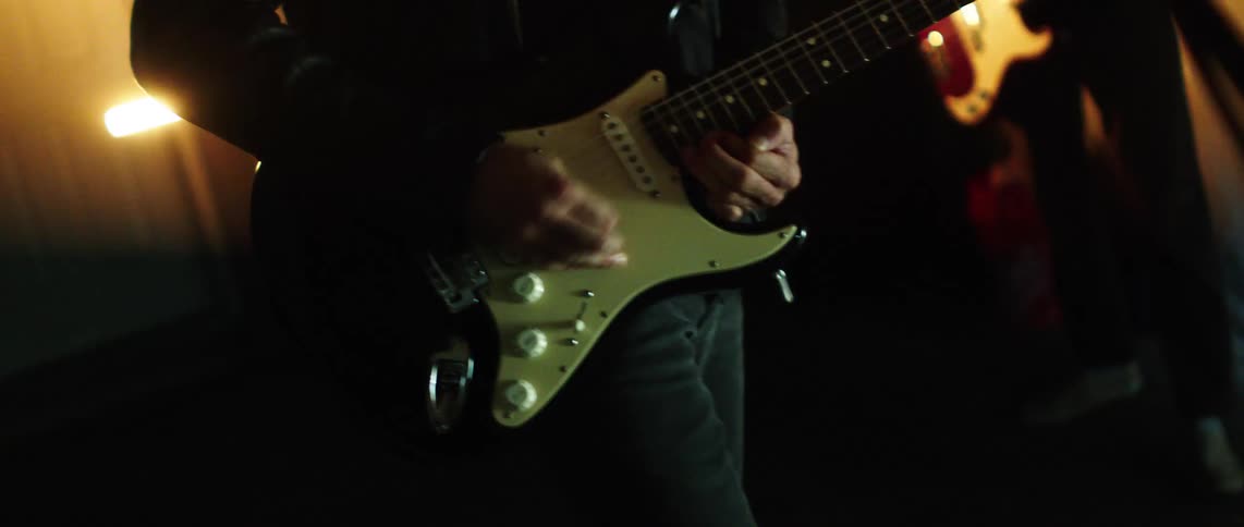 Two musicians play electric guitars during a live performance on stage