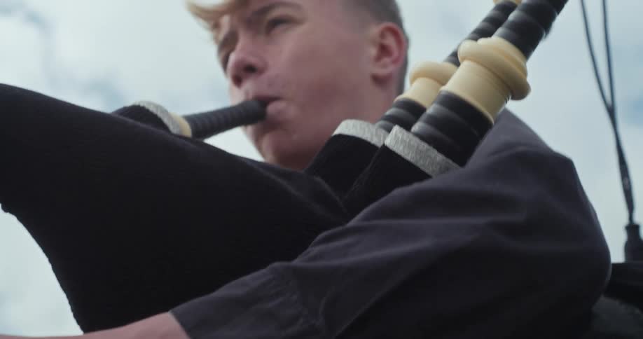 The teenager is playing bagpipes on a windy day