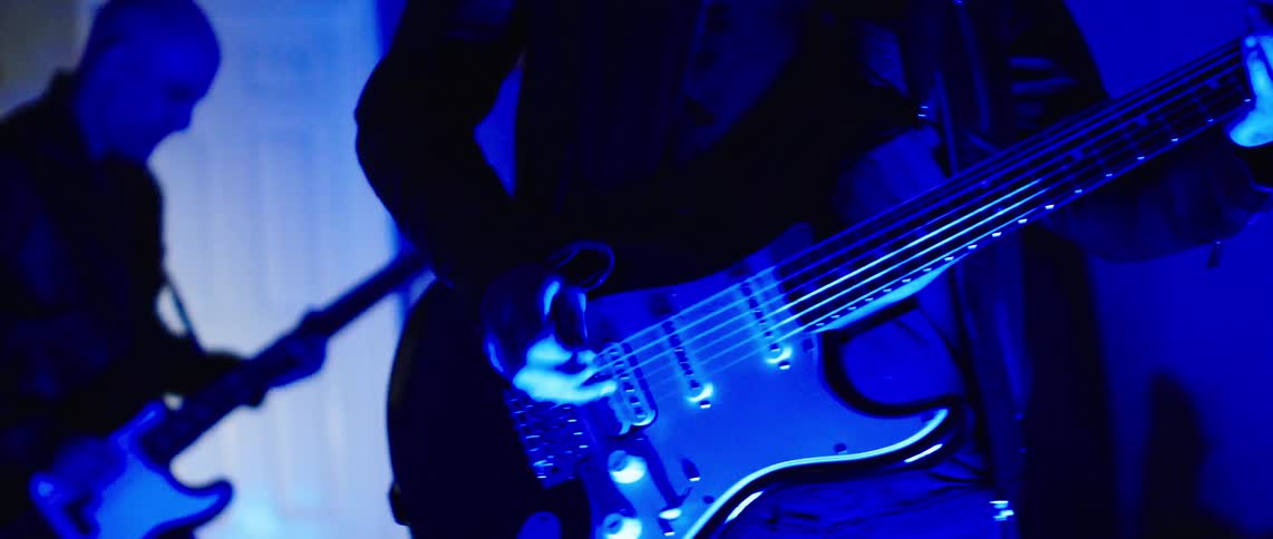 Two guitarists playing and singing on a stage at night