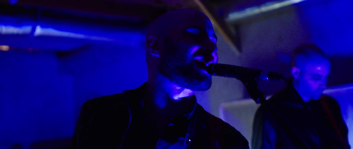 Man singing and another playing guitar in a performance