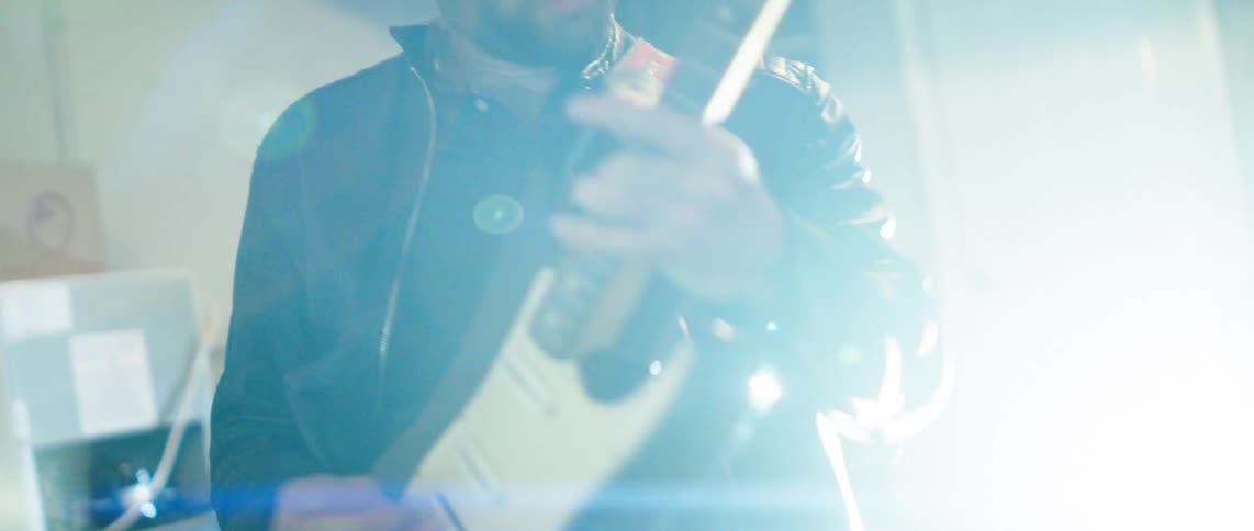 Two men in an indoor space performing guitar