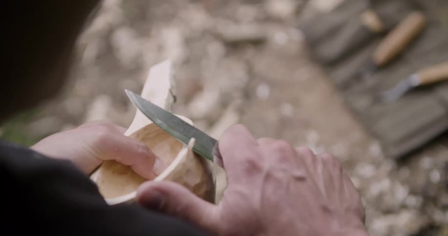 The man slowly carves a bowl from wood