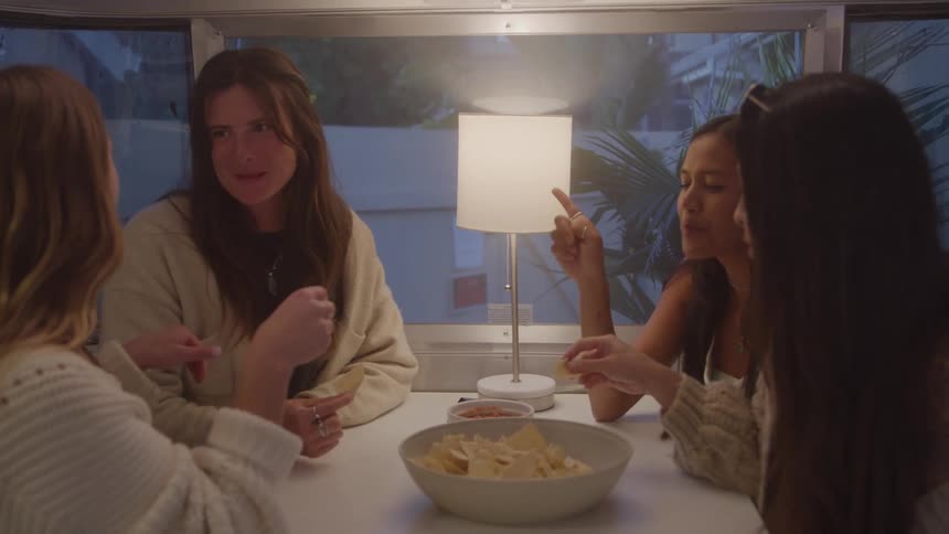 Group of women sitting at a table eating nachos and talking